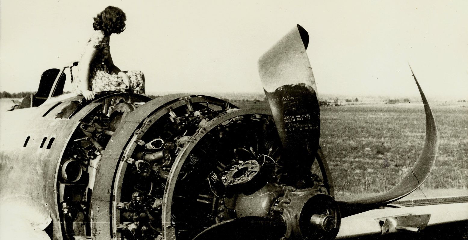 Een meisje kijkt vanaf het wrak van een Amerikaans gevechtsvliegtuig over de velden bij Groesbeek. Volg de Oorlogspaden door Gelderland en ontdek deze en andere verhalen uit de Tweede Wereldoorlog. Foto: Vrijheidsmuseum